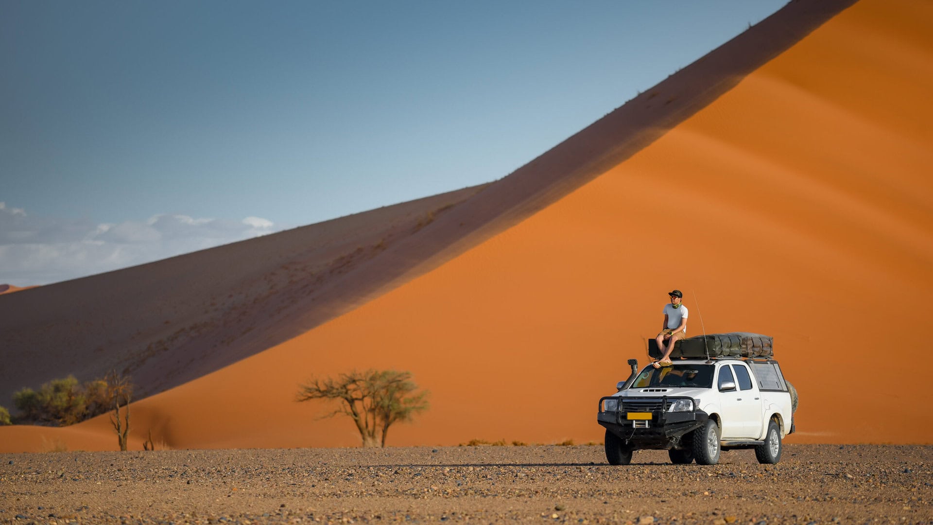 gay-urlaub-namibia-wueste-duene-reise-offroad-lgbtqia-tourist-sitting-on-camper-car