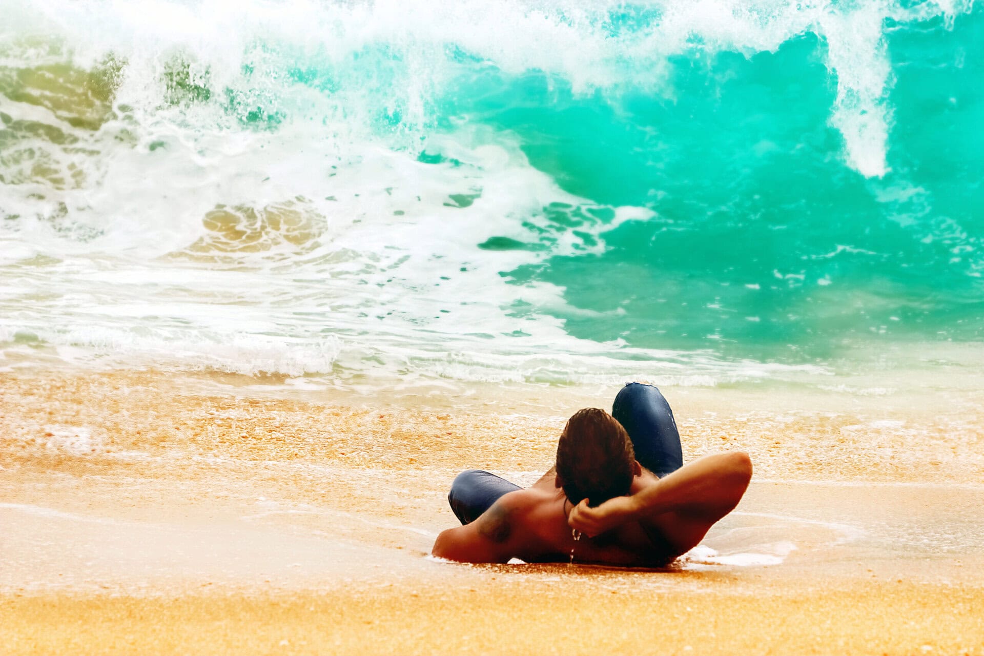 Mann in blauer Jeans liegt entspannt im Sand – Symbolbild für Erholung und Strandurlaub auf einer Gay Reise durch Sri Lanka