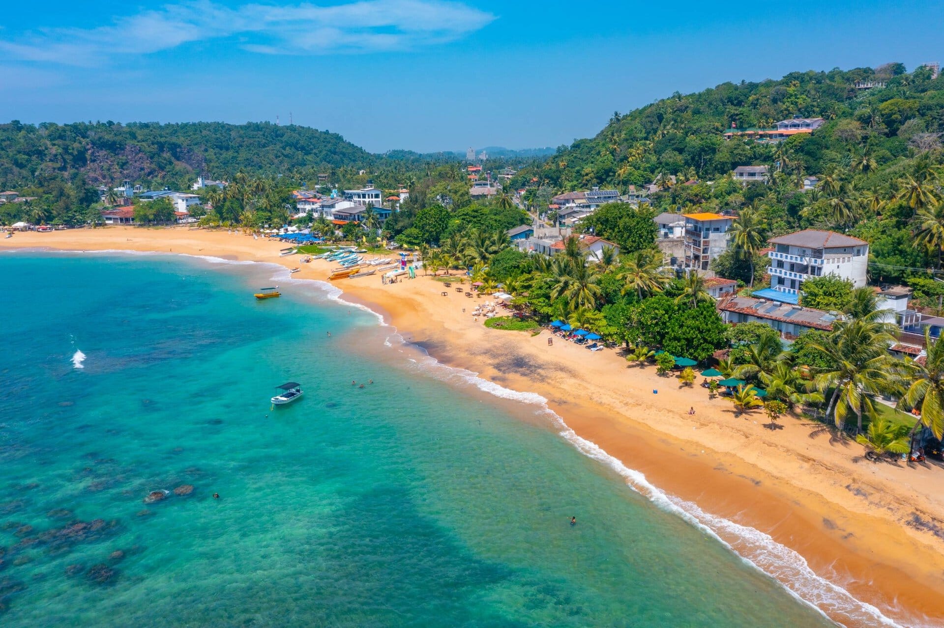 Luftaufnahme des Unawatuna Beach an der Südküste Sri Lankas mit türkisblauem Meer, palmengesäumtem Sandstrand und tropischer Vegetation